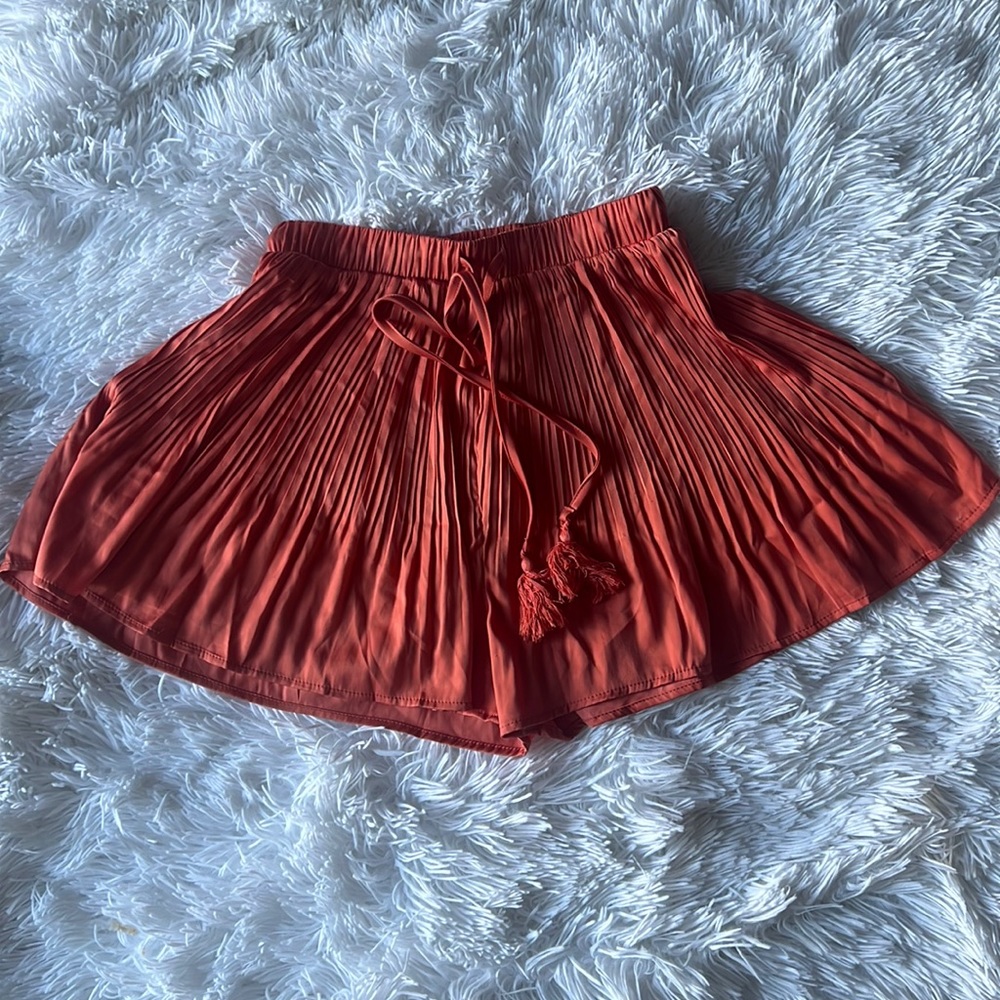 Satin-feel pleated shorts with tassel.